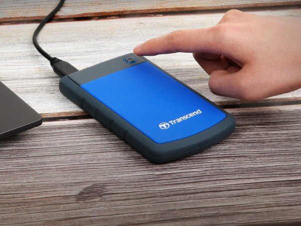 PRE-Loved - Transcend StoreJet 1TB Rugged Blue Portable Hard Drive - with Lightning-Fast Transfers in use on a table.
