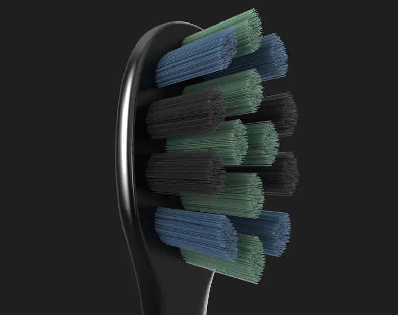 Close-up of the toothbrush head of the Aeno DS2S Sonic Electric Toothbrush with green and blue bristles on a black background