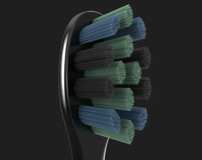 Close-up of the toothbrush head of the Aeno DS2S Sonic Electric Toothbrush with green and blue bristles on a black background