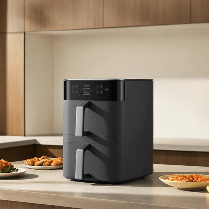 Black air fryer on a kitchen counter with plates of food in the background