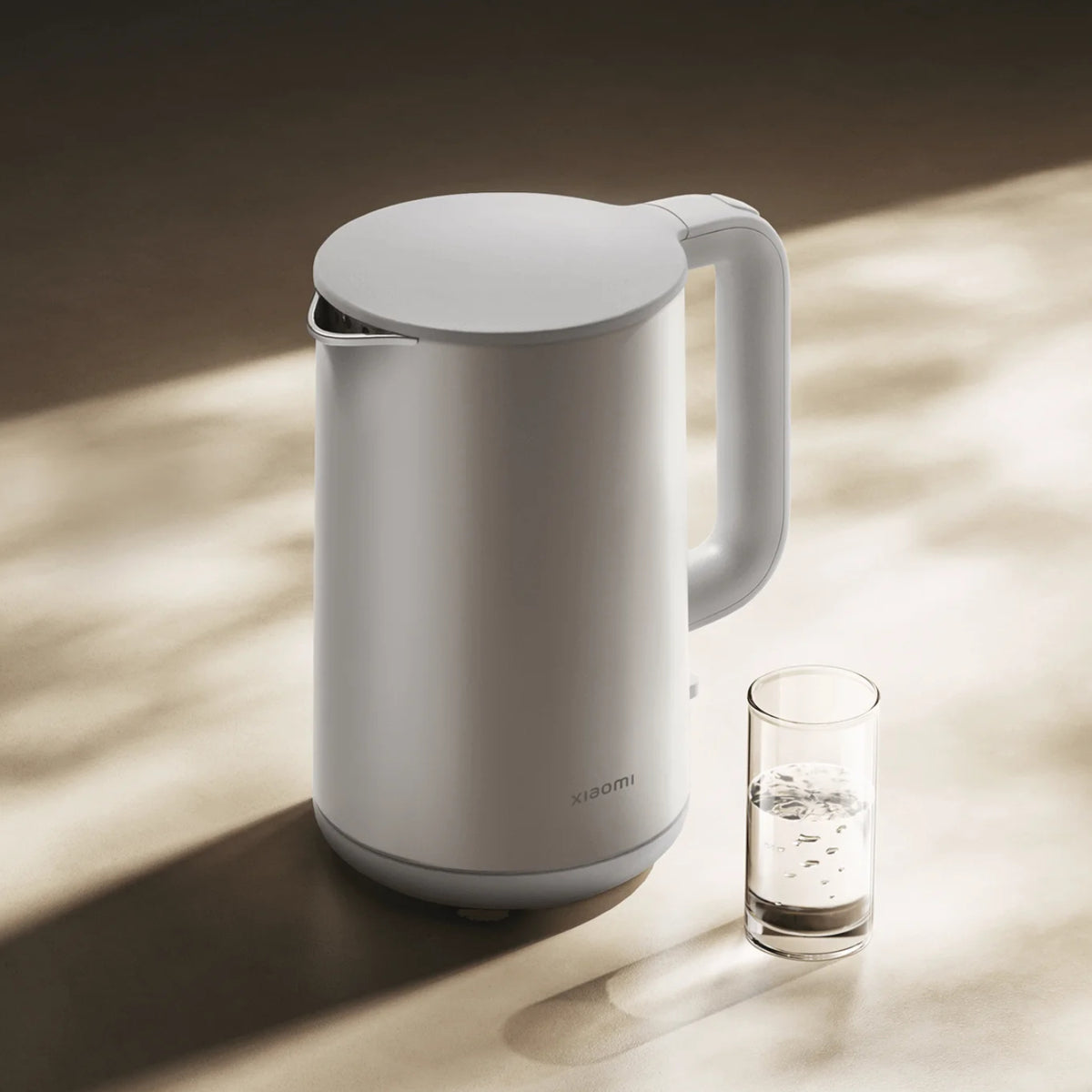 White electric kettle on a wooden surface with a glass of water next to it