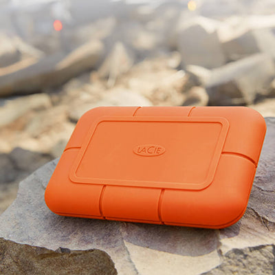 Orange LaCie hard drive on a rocky surface