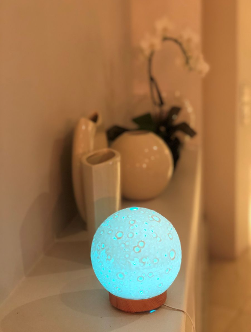 3D Moon Lamp Aromatherapy Diffuser with Wooden Base – Relaxing and Stylish Home Decor glowing softly in cozy room setting