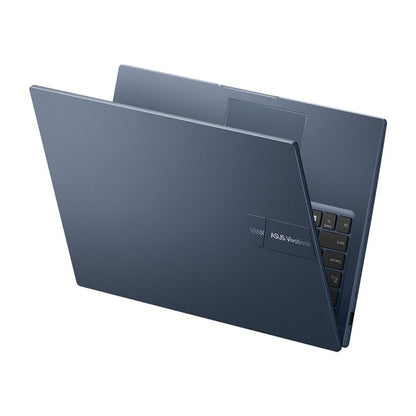 A dark slate blue ASUS Vivobook laptop shown open at an angle against a plain white background, displaying its inner lid, keyboard, and hinge area.